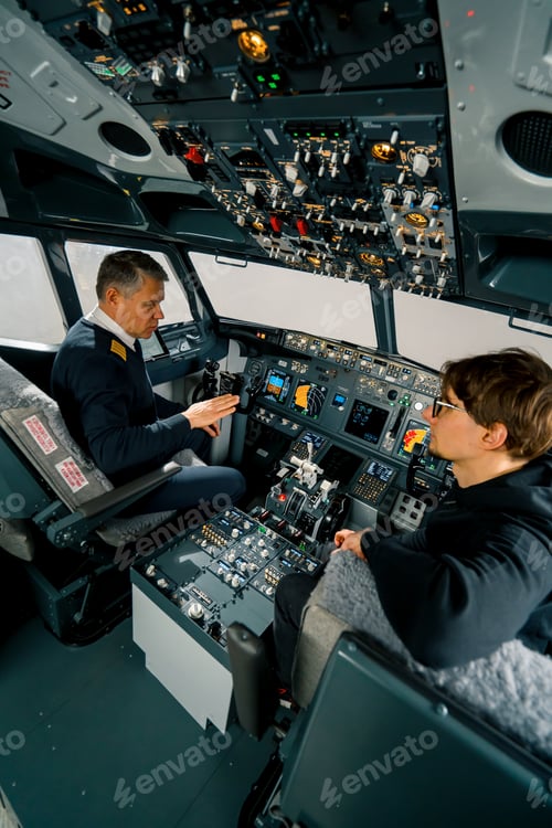 Preview: An experienced pilot instructs a young student before a training flight in the cockpit simulator
