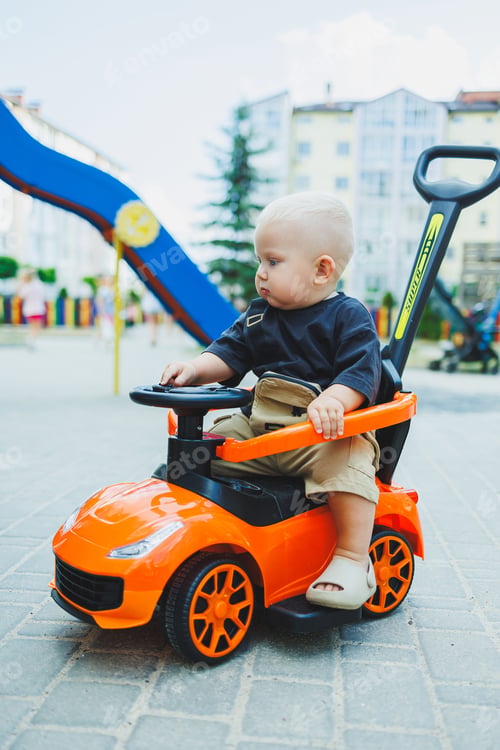 Preview: A little boy, 1 year old, sits in a plastic car. A machine for feeding babies. Tolokar for children.