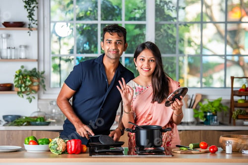 Preview: Indian young husband wife preparing food in the kitchen