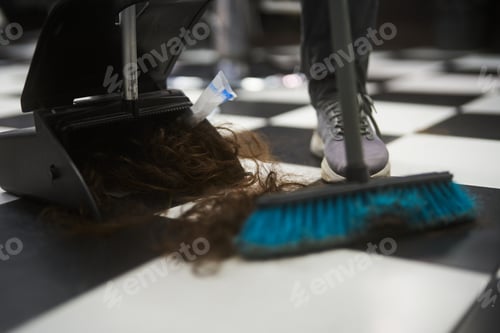 Preview: Hair being cleaned up from a black and white checkered floor in a salon