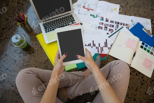 Preview: Woman using digital tablet sitting on floor at creative office