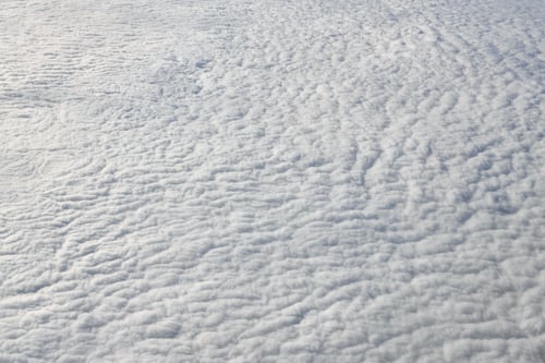 Preview: Breathtaking over clouds view from aircraft window, thick white blue clouds looks like soft foam