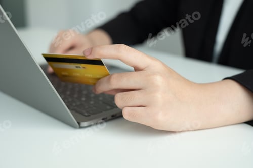 Preview: The businesswomen's hand is holding a credit card and using a laptop for online shopping and interne