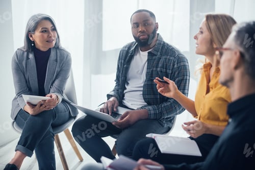 Preview: selective focus of multicultural colleagues with gadgets sitting and talking in office