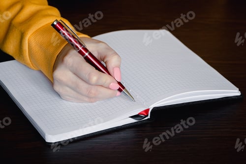 Preview: Woman writing in blank notebook. Close-up of hand holding pen.