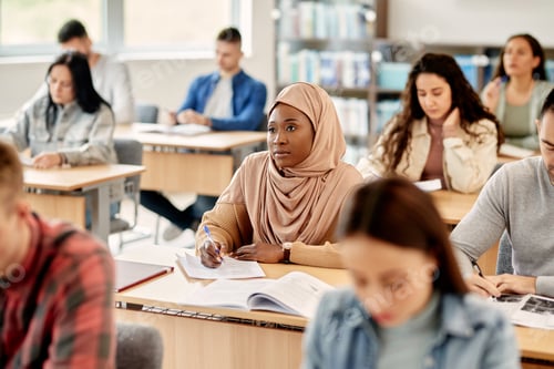 Preview: African American Islamic student taking notes while attending a lecture at the university.