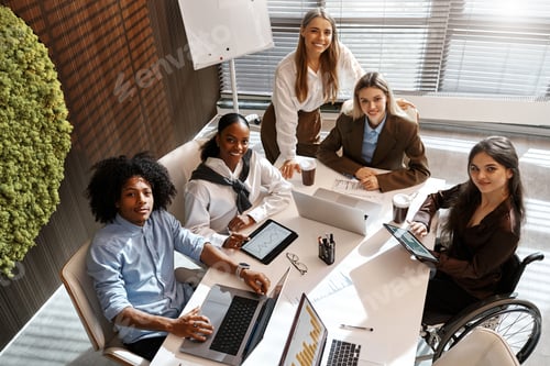Preview: Diverse business team analyzing charts during office meeting from top view