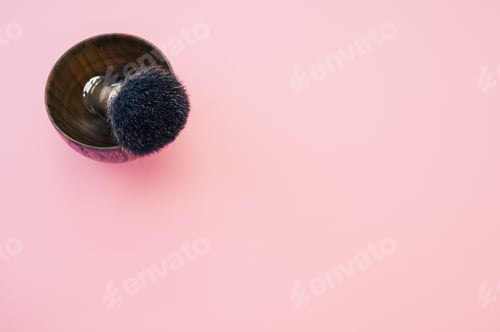Preview: High angle shot of a wooden shaving water bowl near a shaving brush isolated on a pink background