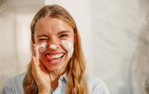 Preview: A Joyful Woman Happily Washing Her Face with a Cleanser in a Bright and Inviting Bathroom