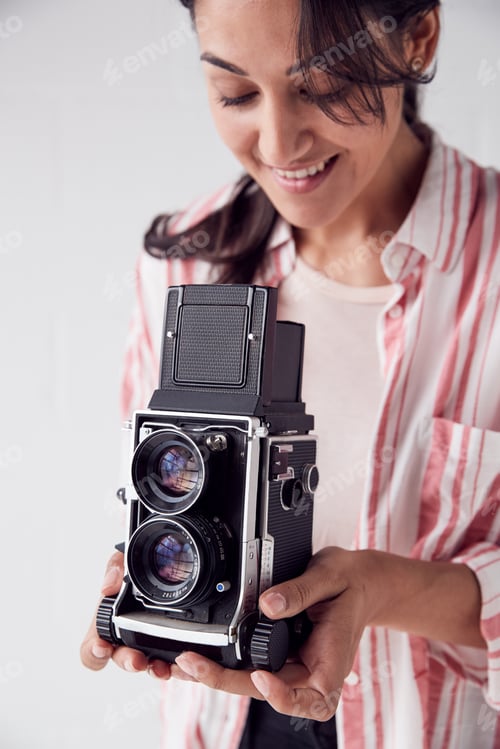 Preview: Female Photographer With Vintage Medium Format Camera On Photo Shoot Against White Studio Backdrop