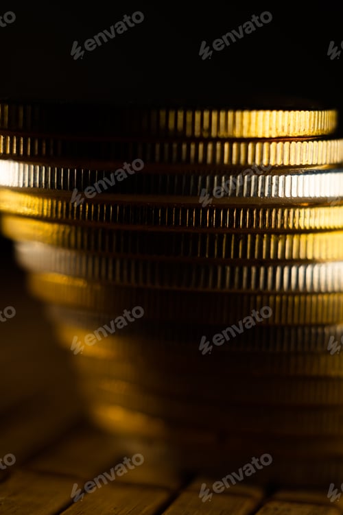 Preview: Vertical shot of a stock of coins with dark background under spotlight