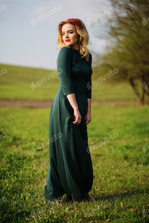 Preview: Yong elegance blonde girl at green dress on the garden in spring.