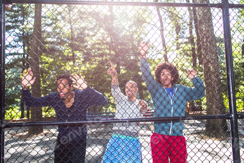 Preview: Young men by wire fence in park