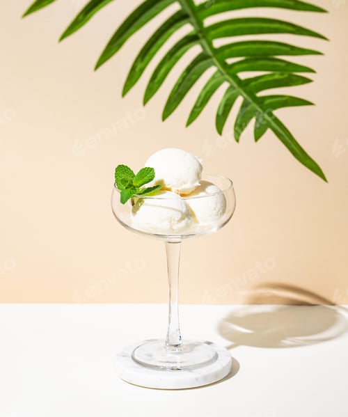 Preview: Scoops of vanilla ice cream with mint leaf in a tall glass on a beige white background