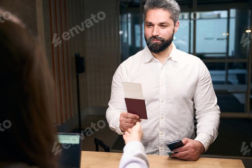 Preview: Serious young Caucasian businessman checking into hotel