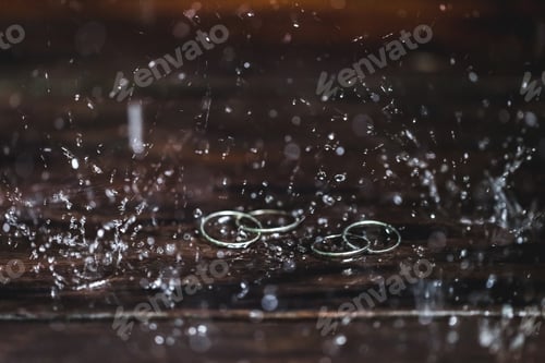 Preview: Double white gold wedding rings under water drops splash close up. Studio macro shot