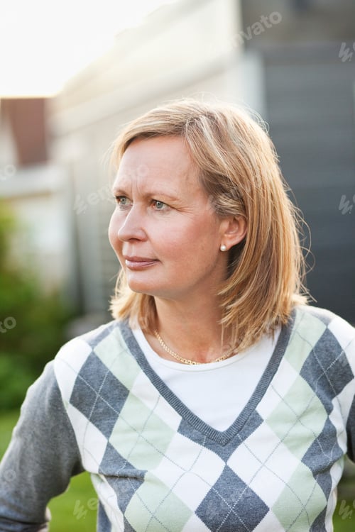 Preview: Close-up of thoughtful woman looking away while standing in back yard