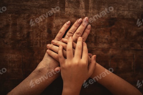 Preview: Hands of different ages and skin tones placed together on a wooden surface