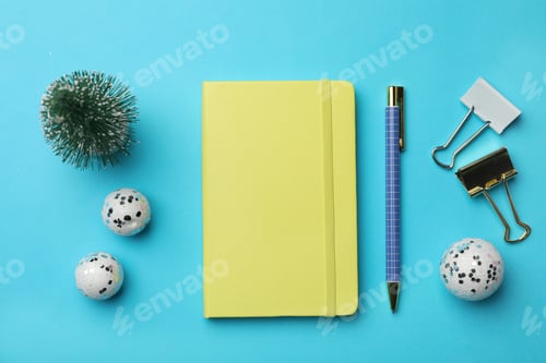 Preview: Yellow planner and Christmas decor on light blue background, flat lay