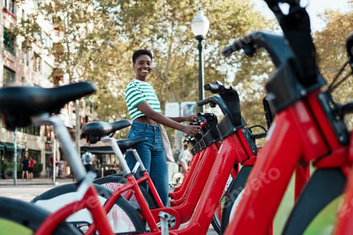 Preview: African American young woman using an mobile app to rent a shared bicycle