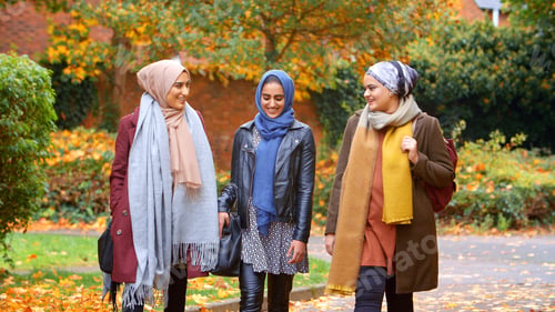Preview: Group Of Young British Muslim Female Friends Walking Through City Park In Autumn