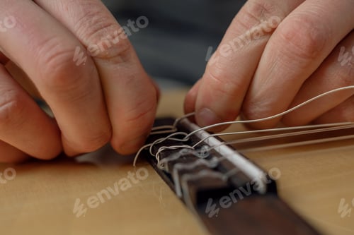 Preview: Male hands change the string on an acoustic guitar, close-up