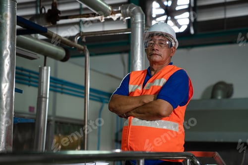 Preview: Engineering man in protective safety uniform working with clipboard at factory.