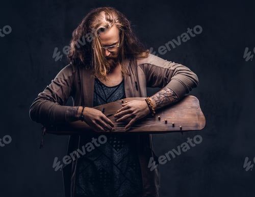 Preview: Redhead hipster male playing on a Russian traditional musical instrument - gusli