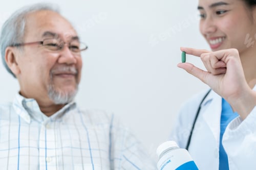 Preview: Asian doctor giving medicine tablet to senior man for sickness treatment