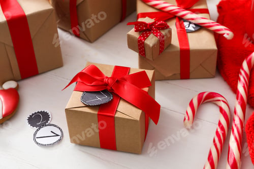 Preview: Gift boxes and Christmas candy canes on white wooden table. Advent calendar