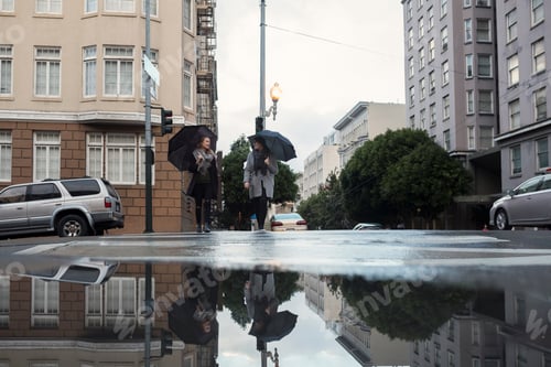 Preview: Two women with umbrellas walking in city