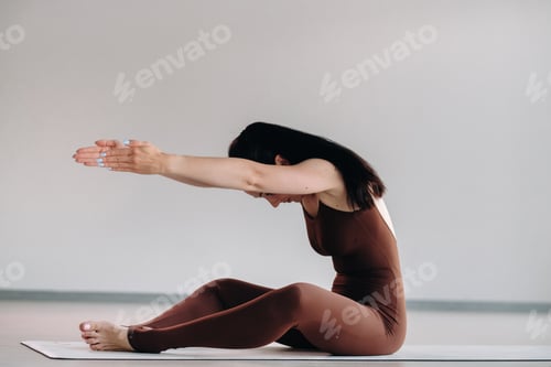 Preview: a woman in a brown suit does yoga in a fitness room . Healthy lifestyle, fitness, training, self
