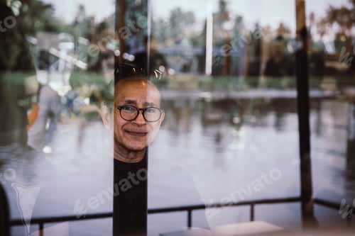 Preview: Man wearing glasses and smiling behind a glass window