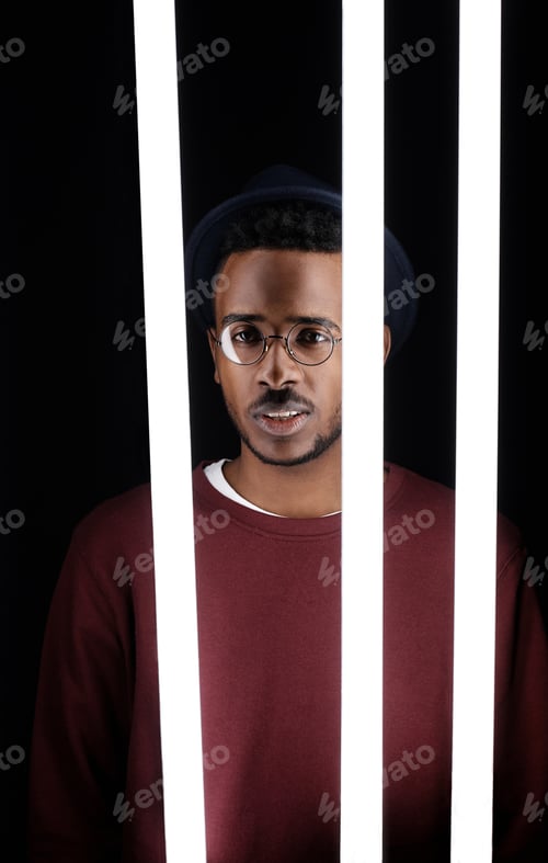Preview: Studio Portrait of Young Black Guy behind Neon Tube Lamps