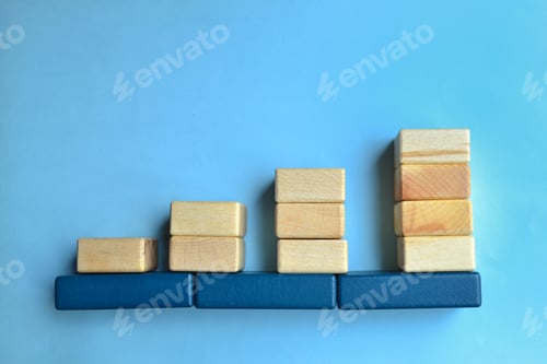 Preview: Arranged wooden tiles rise against a blue background, inflation concept