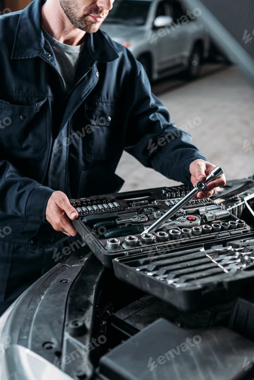Preview: cropped view of mechanic with tool case in auto repair shop