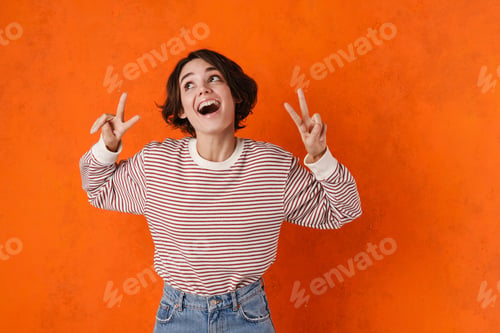 Preview: Young brunette woman screaming while showing peace gesture