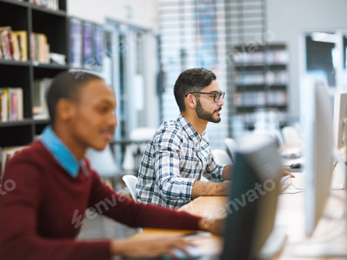 Preview: Shot of two young focused students working o a computer together inside of a library