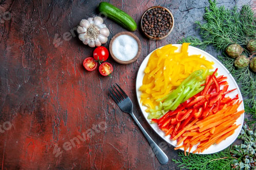 Preview: top view colorful cut peppers on plate fork salt and black pepper tomatoes garlic cucumber on dark