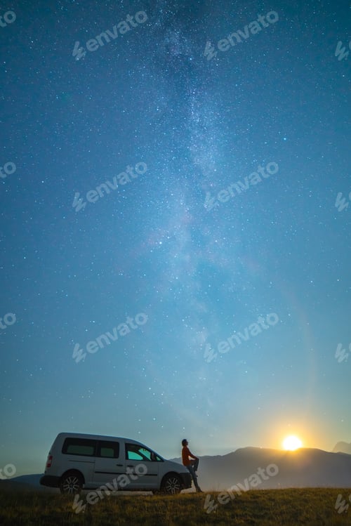 Preview: The man stand near the car on the background of the milky way. night time.
