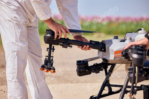 Preview: Operator in a white uniform preparing agrodrone for flying above the field.