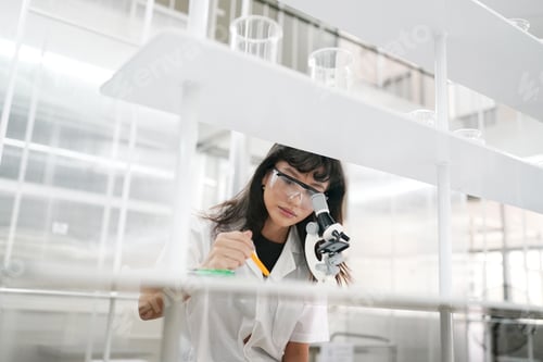 Preview: Young scientist in white lab coat working with binocular microscope in the material science lab