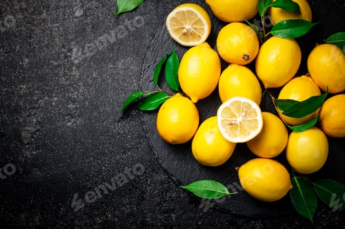 Preview: Juicy lemons with leaves on a stone board.