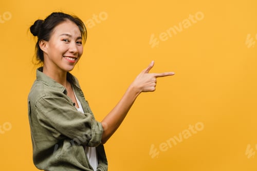 Preview: Portrait of young Asian lady smiling with cheerful expression on yellow background.