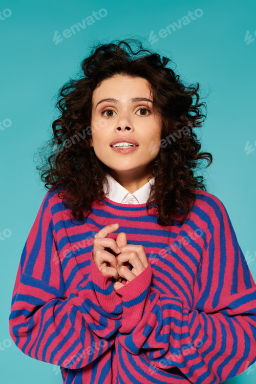 Preview: Young woman expresses joy in vibrant fashion against a bold turquoise backdrop