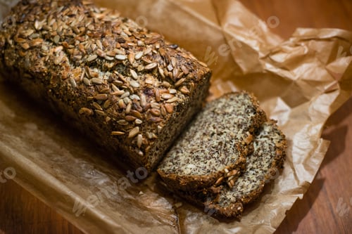 Preview: Artisanal seeded bread loaf freshly sliced on a wooden table.