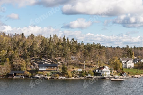 Preview: view from the ship to the rocky coast of Sweden. typical swedish houses on the rocks. cloudy sky