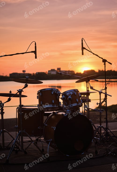 Preview: Silhouette drum kit by the lake in the warm evening
