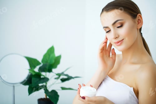 Preview: Young Woman Applying Moisturizer in Bright Room