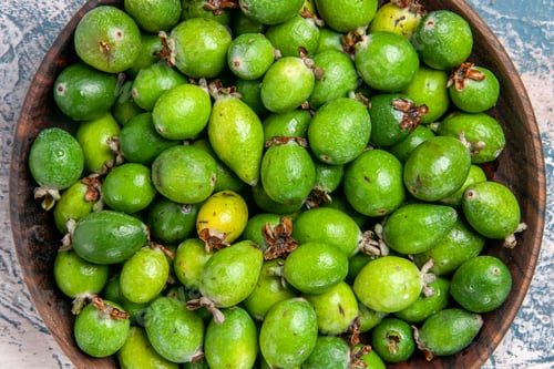 Preview: Close up view of delicious fresh feijoas in a brown pot on gray background